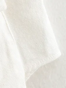Detailed macro view of the white twill fabric texture on a sleeveless denim shirt jacket.