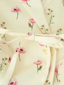 Détail en gros plan de l'imprimé fleuri rose romantique sur le blazer crème.