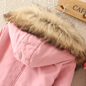 Nahaufnahme eines stilvollen rosa Wintermantels mit Kapuze und großem Kunstpelzkragen