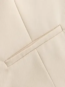 Close-up detail of a beige vest waistcoat showing pocket and twill fabric texture