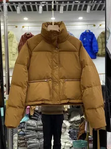 Nahaufnahme einer braunen Winter-Pufferjacke mit Stehkragen und Reißverschlusstaschen.