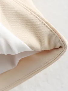 Close-up macro shot showing beige twill fabric texture and neat white lining of women's vest