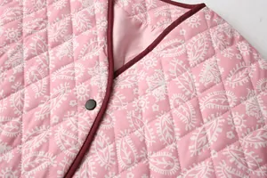 Close-up of pink quilted jacket with white paisley print and burgundy V-neck trim