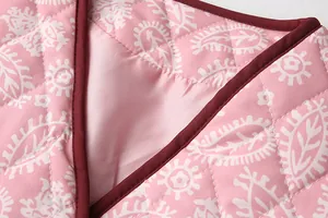 Close-up detail of quilted pink paisley fabric with elegant diamond stitching and trim