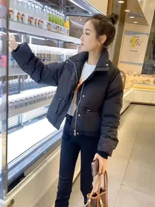 Schwarze Winter-Pufferjacke für Damen mit Stehkragen in einer Lifestyle-Szene gezeigt