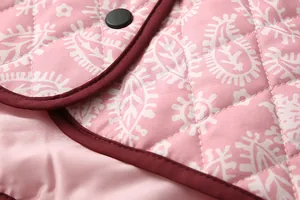 Detailed macro view of pink quilted jacket featuring white paisley print and stitching.