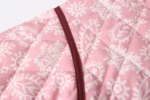 Detailed macro shot of pink quilted fabric with white paisley print and burgundy trim