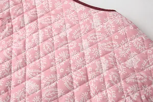 Close-up detail of pink quilted polyester fabric with white paisley print for winter vest