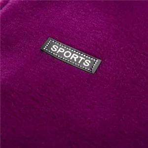 Macro-detail van zachte paarse polar fleece stof met een zwarte SPORTS logo patch