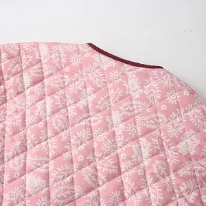 Close-up detail of pink quilted cotton jacket with white paisley print pattern