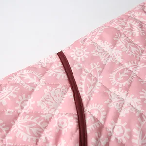 Close-up view of pink quilted fabric with white paisley and floral pattern details