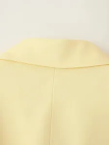Vue détaillée montrant la texture fine du tissu et les coutures d'un col de blazer jaune