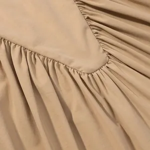 Close-up detail of beige pleated fabric texture on a minimalist sleeveless vest top