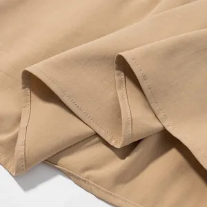 Close-up detail of smooth khaki fabric and stitching on a minimalist sleeveless vest top
