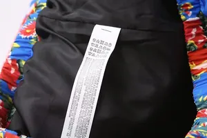 Close-up detail of the inner wash care label and black lining of floral printed jacket coat