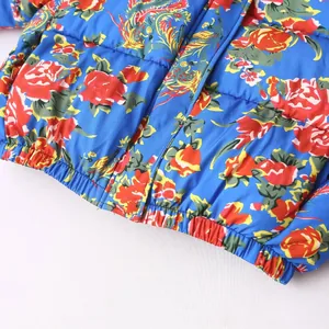 Close-up detail of a blue puffer jacket featuring vibrant floral and phoenix print patterns.