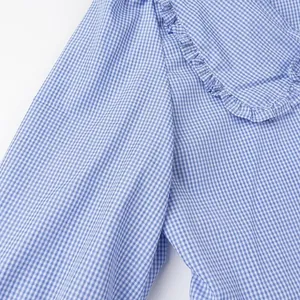 Detailed macro shot of blue and white gingham blouse fabric with ruffled edge accents