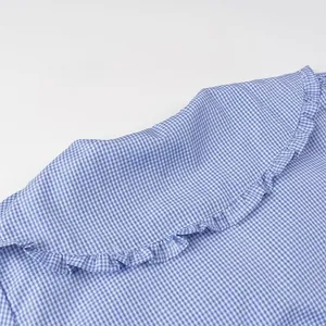 Detailed close-up of blue gingham shirt with ruffled Peter Pan collar and soft fabric.