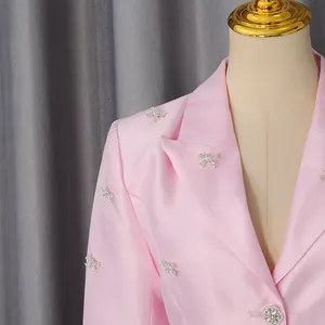 Close-up of pink satin blazer with sparkling rhinestone bow embellishments and floral button