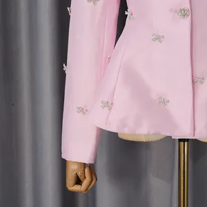 Close-up of pink satin blazer with crystal-embellished bow details and texture