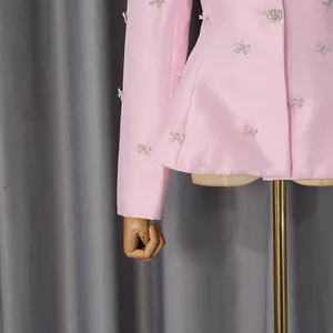 Close-up of pink satin suit jacket with sparkling rhinestone bow embellishments