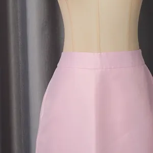 Close-up detail of the waistline and fabric texture of a pink satin skirt on a mannequin