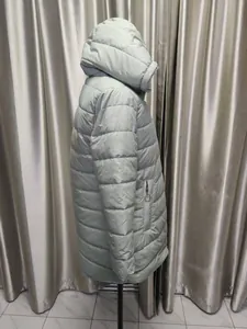 Side view of a pale mint green women's mid-length hooded puffer coat with quilted texture