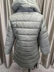 Back view of a women's longline quilted puffer coat in a sage green color