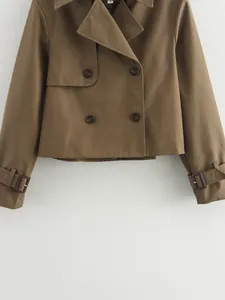 Detail view of khaki double-breasted cropped trench coat with lapel and sleeve buckles.