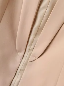 Gedetailleerde weergave van de revers en de stiksels van een roze damesblazer jas