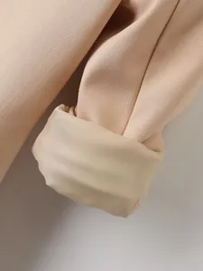 Detailopname van de beige blazer mouwmanchet met fijne stoftextuur en binnenvoering.