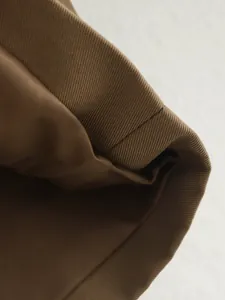 Macro view showing fine twill texture and premium stitching of a brown windbreaker