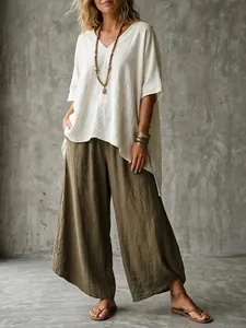 Model wearing loose white V-neck linen tunic and olive wide-leg trousers