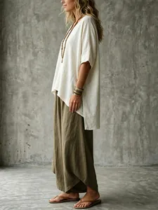 Side view of woman in a bohemian loose white V-neck blouse and olive green wide pants