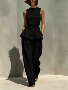 Vista completa del set minimalista nero in cotone e lino con top peplum e pantaloni a gamba larga.