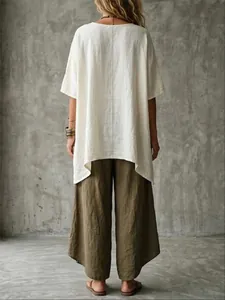 Back view of a woman wearing a loose off-white linen tunic and olive wide-leg pants