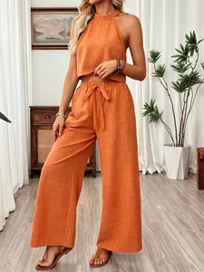 Two-piece summer set with orange halter neck crop top and belted wide-leg trousers
