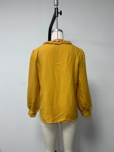 Detailed back view of a yellow long-sleeve cotton shirt with a ruffled collar on a mannequin