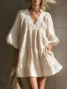 Detail view of the elegant lace V-neck and ruffled sleeves on this cream mini dress.
