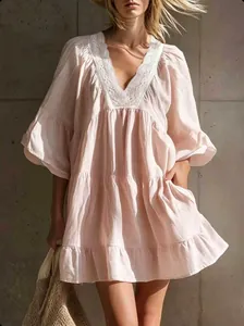 Close-up detail of white lace trim on the V-neckline of a pink tiered resort summer dress