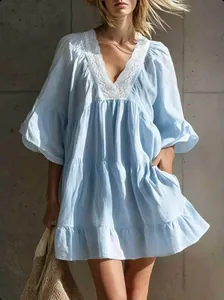 Detail view of light blue tiered vacation dress with delicate white lace V-neckline trim