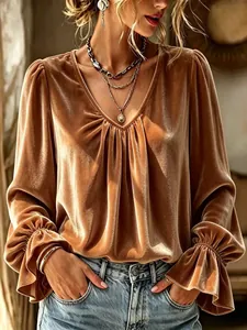 Detail view of an elegant caramel velvet V-neck blouse featuring ruffled cuffs and pleats.