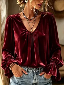 Detail of burgundy velvet shirt featuring a deep V-neck and pleated long sleeves.