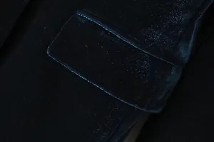 Dettaglio della tasca e della texture in velluto su una giacca blazer verde scuro