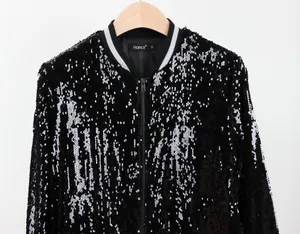 Detalle de chaqueta bomber de lentejuelas negras con cuello elástico plateado y cremallera