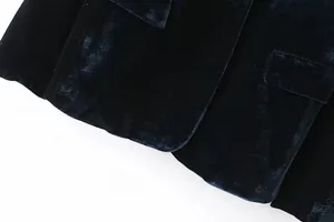 Dettaglio ravvicinato del tessuto di velluto verde scuro su un blazer da donna