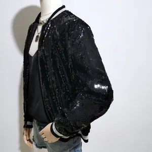Detailaufnahme einer schwarzen Pailletten-Bomberjacke mit gestreiften Bündchen.