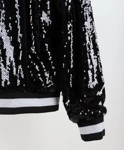 Detalle de cerca de lentejuelas negras y puños de canalé en una chaqueta bomber