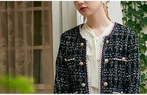 Close-up of a classic black and white tweed jacket with gold buttons and tri-color trim.