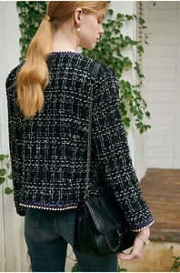 Detail view of black and white plaid tweed jacket with colorful woven trim on cuffs